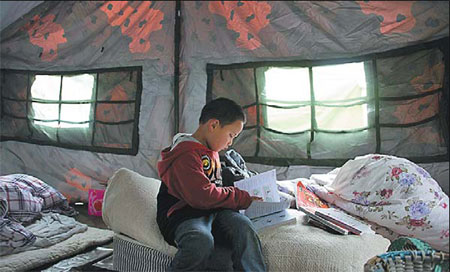 Yang Xuxue, 5, reading in the tent that now serves as his home. Life resumes in 'isolated island'