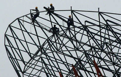 Workers perch on a steel structure at the construction site for a giant roof in Xiangfan, central China's Hubei province April 24, 2006.