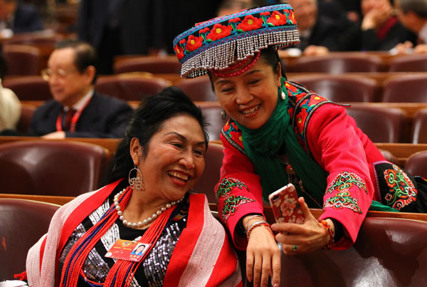 Two members of the Chinese People's Political Consultative Conference National Committee capture the memeries with a mobile phone at the opening ceremony of this year's session in Beijing. Ethnic group members at CPPCC