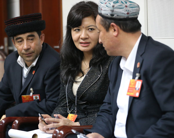 Nurgul Kerim (center) interprets during a panel discussion of the delegation of the Xinjiang Uygur autonomous region on Wednesday. JIANG DONG / CHINA DAILY Wearing translator's hat a big role