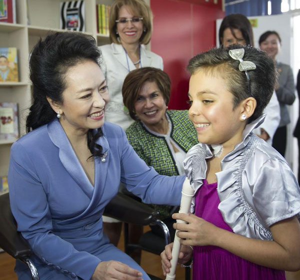 Peng Liyuan communicates with a child during her visit to the National Children's Hospital of Costa Rica, accompanied by Emilce Miranda, mother of Costa Rican President Laura Chinchilla, in San Jose, Costa Rica, June 3, 2013. Peng Liyuan visits children in Costa RicaPne