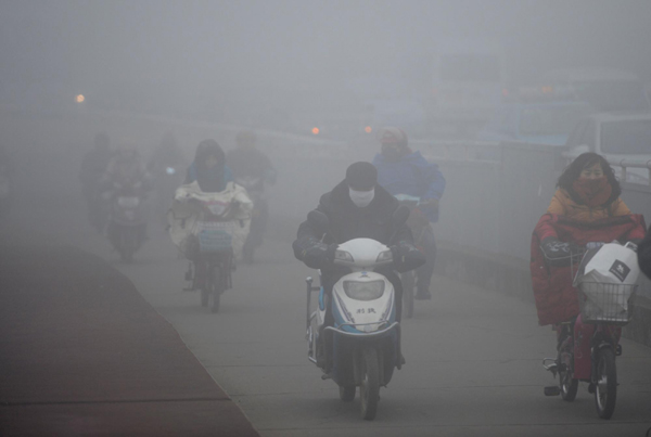 Citizens ride through heavy fog in Nanchang, East China's Jiangxi province, Jan 26, 2013.  China issues blue alert for thick fog