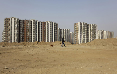 A resident walks with his pet dog on a construction waste hill next to a residential area in Beijing March 22, 2013.  Beijing announces new property rules