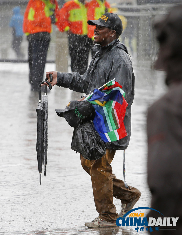 曼德拉追悼會(huì)現(xiàn)場(chǎng)：情侶為偉人海報(bào)打傘