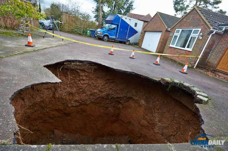 英國(guó)居民房屋前驚現(xiàn)大坑 汽車慘遭“吞噬”