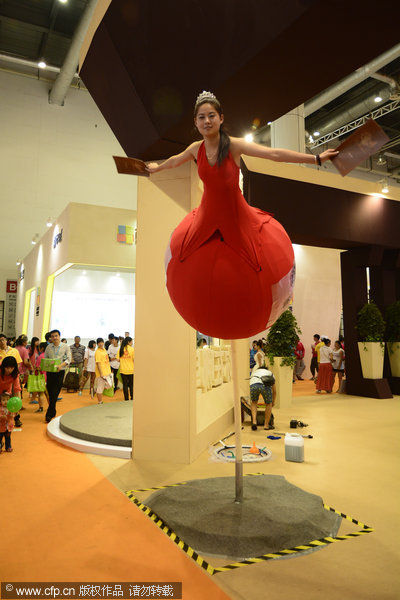A woman in fancy dress flies above the crowd to draw customers during a summer house exhibition in Dalian, July 18, 2013.  The beauty and beasts of selling hot houses