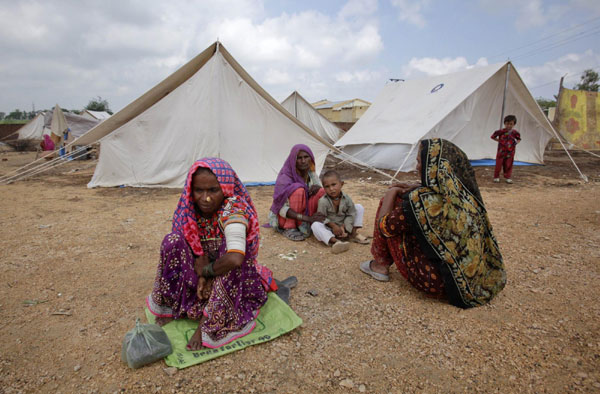 Women displaced by floods sit outside their tents while taking refuge along a road in Golarchi in Badin district of Pakistan's Sindh province Sept 13, 2011. Floods rattle Pakistan, 300,000 homeless
