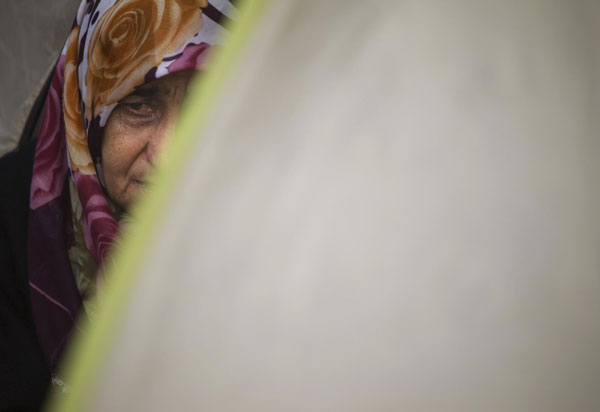 A woman looks on as she sits at her tent near a collapsed building after the earthquake in Ercis Oct 26, 2011. Turkey struggles to shelter people after quake