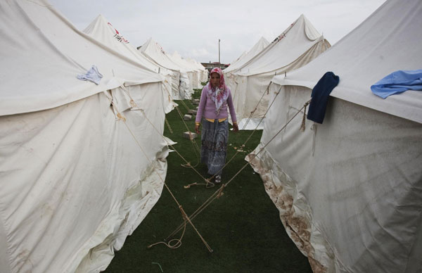 A woman walks past tents set up at a stadium currently used as a relief shelter campsite for earthquake victims in Ercis Oct 26, 2011. Turkey struggles to shelter people after quake