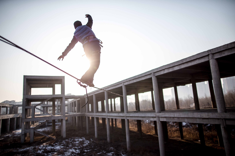 Tightrope walker Zhang Liang walks on a thin rope at an abandoned construction site in Beijing, Jan 26, 2013. Dizzy trend of tightrope walking