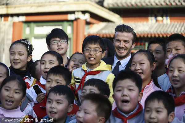 David Beckham, back center, poses for a photo with local students during his visit to the former residence of Soong Ching-ling in Beijing, on March 24, 2013, as his five-day China visit came to an end. Beckham catches up with Chinese culture on last stop