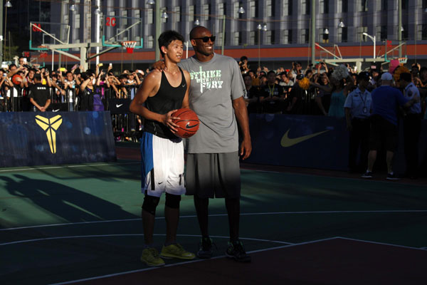 Los Angeles Lakers NBA star Kobe Byrant poses with the top scoring player from a match at a local community center in the southern Chinese city of Shenzhen August 4, 2013. Kobe Byrant meets fans in Shenzhen