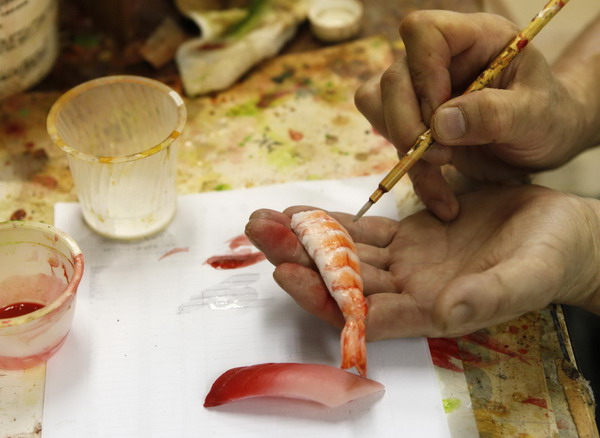 A worker paints a plastic shrimp model to be used as a decoration on an iPhone case at Suetake Sample, a plastic food model maker, in Yokohama, near Tokyo July 29, 2011. Sushi for your iPhone case
