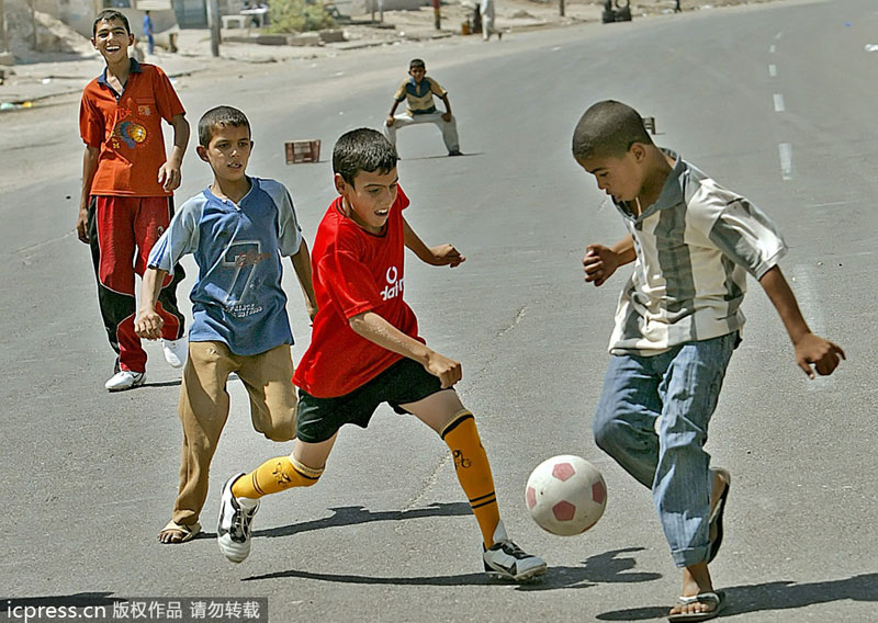 Iraqi boys play football in an empty street in central Baghdad, June 21, 2006. Public sports in post-war Iraq