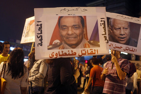 Activists from a group called 'Third Square', which promotes a middle way in the rift between the Muslim Brotherhood and supporters of the army's overthrow of Egyptian President Mohamed Mursi, carry posters of key former army figures as they gather to oppose both parties at Sphinx Square in Cairo July 30, 2013.  Egypt's rulers to move against Brotherhood vigils
